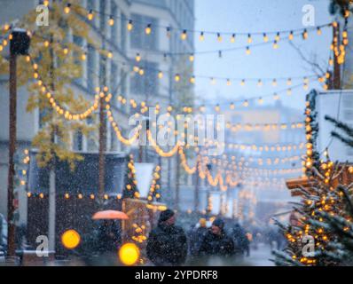 Eine magische Szene auf dem Zürcher Weihnachtsmarkt in der Schweiz, mit funkelnden Lichtern und Schneefall, die ein winterliches Wunderland und defokussiertes Bokeh schaffen Stockfoto