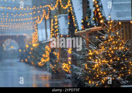 Eine magische Szene auf dem Zürcher Weihnachtsmarkt in der Schweiz, mit funkelnden Lichtern und Schneefall, die ein winterliches Wunderland und defokussiertes Bokeh schaffen Stockfoto