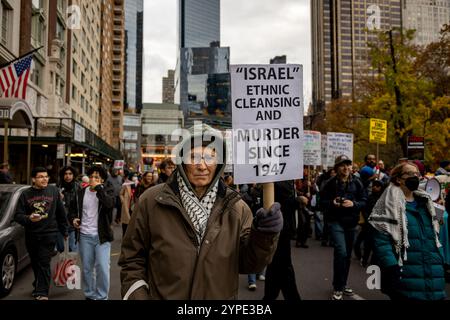 New York, Usa. November 2024. ? NEW YORK, NEW YORK - 29. NOVEMBER: A? Die Person trägt während des Internationalen Tages der Solidarität mit dem palästinensischen Volk am 29. November 2024 in New York ein Schild mit der Aufschrift "Israel, ethnische Säuberung und Mord seit 1949". Proteste fanden in Dutzenden von Städten auf der ganzen Welt statt, darunter Los Angeles, Chicago und Denver, sowie in anderen großen US-Städten. (Foto: Michael Nigro/SIPA USA) Credit: SIPA USA/Alamy Live News Stockfoto