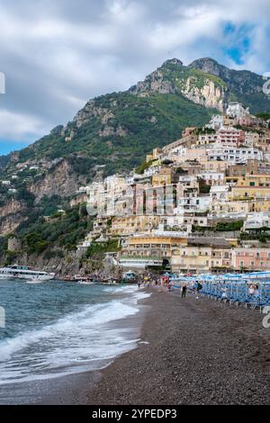 Die farbenfrohen Gebäude von Positano stürzen sich an den Sandstrand, wo die Sonne aufgeht. Sanfte Wellen harmonieren mit der ruhigen Morgenatmosphäre entlang der Küste. Stockfoto