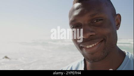 Vorderansicht eines afroamerikanischen männlichen Freiwilligen, der auf die Kamera am Strand blickt Stockfoto