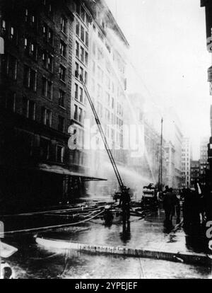 Feuerwehrmänner sprühen Wasser auf das brennende Asch-Gebäude während des Brandes der Dreieck-Shirtwaist-Fabrik vom 25. März 1911. Der Brand der Triangle Shirtwaist Factory war einer der schlimmsten Industrieunfälle in der US-Geschichte. Im 10. Stock des Asch-Gebäudes brach ein Feuer aus. Die Brandausgänge waren verschlossen, die Brandausgänge unzureichend und die Leiter der Löschfahrzeuge waren nicht lang genug. 146 Menschen wurden getötet, von denen 62 in den Tod sprangen, um den Flammen zu entgehen. Dieses Foto zeigt deutlich, dass die Leitern nur den 6. Stock erreichten und das Feuer im 10. Stock war. Stockfoto