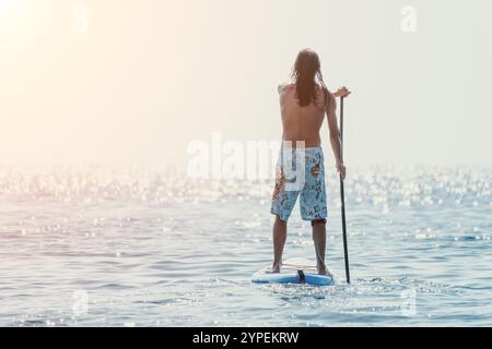 Man Paddle Boarding Ozean - Ein Mann steht auf einem Paddelbrett im Meer und blickt auf den Horizont. Stockfoto