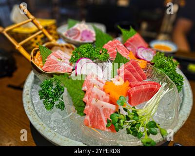 Ein Tablett Sushi mit einer Vielzahl von Fleisch und Gemüse. Das Sushi wird in einer Schüssel mit Deckel serviert Stockfoto