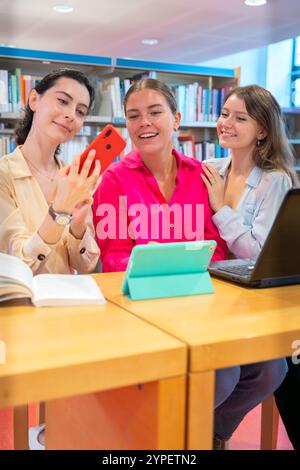 Drei Frauen benutzen Geräte in der Bibliothek Stockfoto