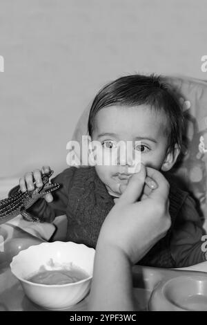Das Baby isst gern, wenn seine Mutter ihn vorsichtig und liebevoll füttert. Schwarzweißfotografie Stockfoto