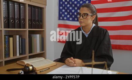 Richterin sitzt im Amt mit amerikanischer Flagge Hintergrund, umgeben von Büchern und Dokumenten, die Autorität und Professionalität vermitteln. Stockfoto