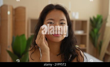 Junge chinesin, die Make-up-Entferner in einem Schönheitssalon mit Spa-Ambiente und ruhiger Inneneinrichtung anwendet Stockfoto