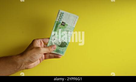 Hand hält koreanischen Won vor gelbem Hintergrund und hebt Währungs- und Finanzkonzepte hervor. Stockfoto