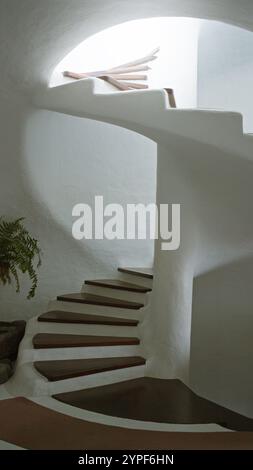 Wendeltreppe auf lanzarote mit glatten weißen Wänden und Holztreppen, die von oben hereinströmen Stockfoto