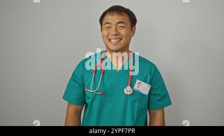 Lächelnde asiatische Krankenschwester in grünen Peelings mit einem roten Stethoskop isoliert auf weißem Hintergrund Stockfoto