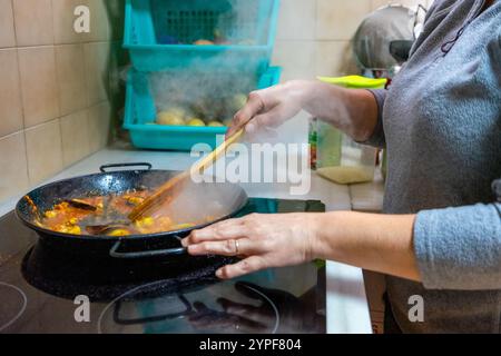 Halblanges Bild einer Frau, die eine Meeresfrüchte-Paella in ihrer Küche zubereitete. Mediterranes Ernährungskonzept. Stockfoto