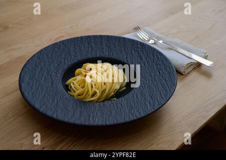 Spaghetti Colatura di Alici mit Knoblauch und Peperoncini auf einer schwarzen Platte Stockfoto