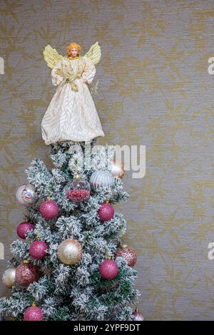Nahaufnahme der festlichen Weihnachtskugeln mit rosafarbenen Motiven, die an einem weihnachtsbaum hängen, dessen Zweige mit weißem Schnee bedeckt sind. Kopierbereich Stockfoto