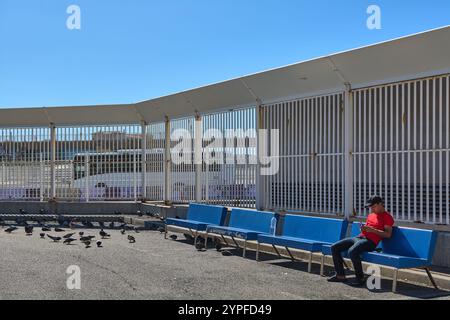 Marseille. Frankreich - 30. November 2024: Junger Erwachsener Pendler mit Smartphone, während sie mit Tauben an der Bushaltestelle warten Stockfoto