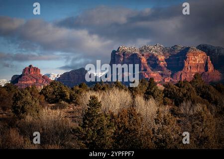 Der Courthouse Rock in Sedona steht majestätisch vor dunklen Wolken und einem überragenden Neuschnee mit Bell Rock im Rahmen links. Stockfoto
