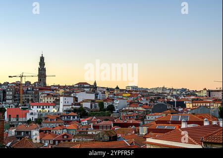 Porto, Portugal - 28. Juli 2024: Dächer verschiedener Gebäude in der Abenddämmerung mit dem Clerigos-Kirchturm und einem Kran in der dist Stockfoto