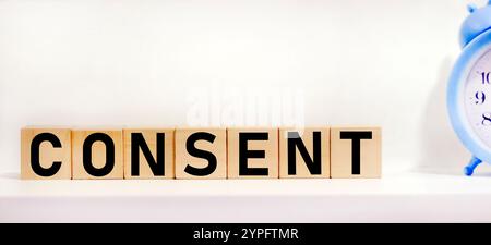 Die auf weißem Hintergrund hervorgehobene Inschrift CONSENT auf Holzwürfeln spiegelt das Konzept von Wirtschaft und Finanzen wider. Stockfoto
