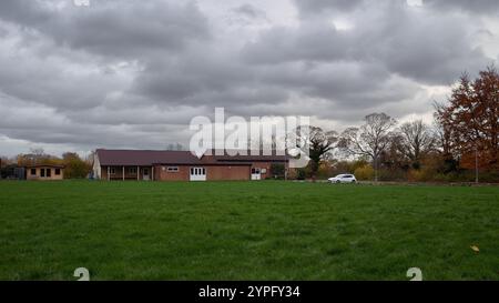 Blick über die Spielfelder zu einem einstöckigen Ziegelklubhaus an einem bewölkten Tag mit einem Baumbestand im Hintergrund Stockfoto