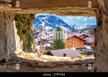 Idyllisches Alpendorf Gstaad mit Blick durch Steinfenster, luxuriöses Winterziel in der Schweiz Stockfoto