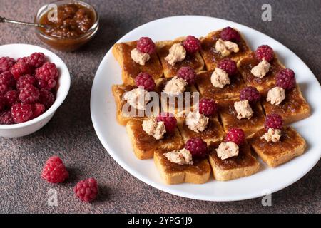 Kanapees mit Gänseleber, Feigendip und frischen Himbeeren auf weißem Teller Stockfoto