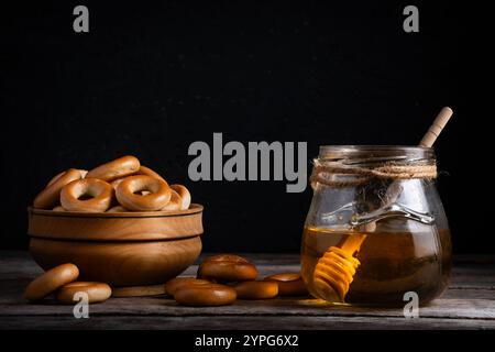 Holztasse mit Bagels und Honig im Glasgefäß auf Holztisch Stockfoto