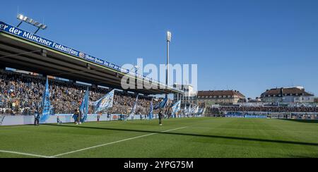 München, Deutschland. November 2024 30. Fahnenschwenker vor der Stehhalle vor Spielbeginn, im Hintergrund die Gaestekurve mit rund 1500 mitgereisten Fans von der Ostsee. GER, TSV 1860 München gegen den FC Hansa Rostock, Fussball, 3. Bundesliga, 16. Spieltag, Saison 2024/2025, 30.11.2024. (DIE DFL-DFB-VORSCHRIFTEN VERBIETEN DIE VERWENDUNG VON FOTOS ALS BILDSEQUENZEN UND/ODER QUASI-VIDEO). Foto: Eibner-Pressefoto/Heike feiner Credit: dpa/Alamy Live News Stockfoto