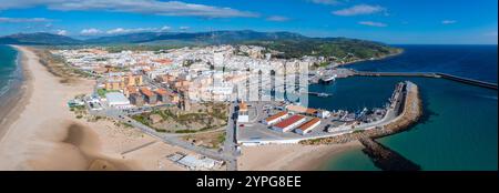 Tarifa, Spanien, ist von oben aus zu sehen, mit weiß getünchten Gebäuden, einem belebten Hafen, Sandstrand und Windturbinen auf den umliegenden Hügeln. Stockfoto