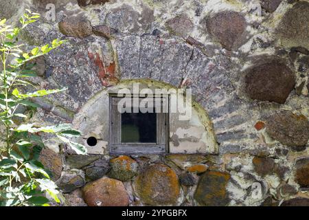 Eine alte Steinmauer mit einem Fenster in einer bogenförmigen Bucht Stockfoto