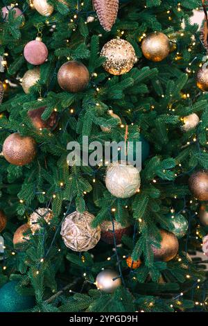 Der Weihnachtsbaum ist mit Gold- und Bronzemedenten und funkelnden Lichterketten verziert. Festliche Dekoration Hintergrund, Tapete, Hintergrund. Festi Stockfoto