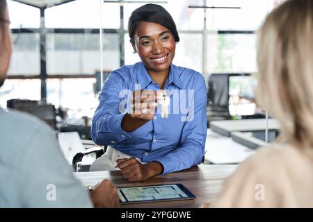Afroamerikanischer Agent gibt Schlüssel, die Eigentum an neue Hausbesitzer verkaufen. Stockfoto