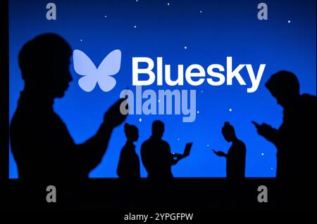 NEW YORK, USA, 30. OKTOBER 2024: BlueSky-Logo. Gruppe junger Leute chatten auf Handy und Laptop bei Bluesky Microblogging Social Networking Servic Stockfoto