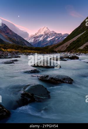 Wunderschöne Landschaft mit lebendigem Sonnenuntergang über Mount Cook mit dem Mond und dem Bach, der im Hooker Valley Track in Neuseeland fließt Stockfoto