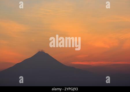 Silhouette des Mount Merapi mit einem rot-orangen Himmel bei Sonnenaufgang. Der Vulkan ist ein Stratovulkan, der sich in Yogyakarta und Zentral-Java befindet Stockfoto