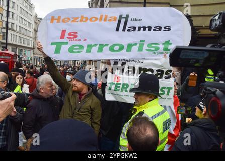 London, Großbritannien. 30. November 2024. Anhänger Israels, die einen Gegenprotest veranstalten, halten ein Anti-Hisbollah- und Anti-Hamas-Zeichen, während Tausende von Menschen in Solidarität mit Palästina marschieren und einen Waffenstillstand fordern und die britische Regierung auffordern, alle Waffenverkäufe an Israel einzustellen, während der Krieg in Gaza anhält. Quelle: Vuk Valcic/Alamy Live News Stockfoto