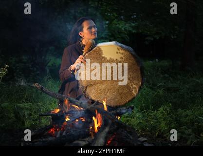 Die schamanische Frau führt nachts ein Ritual im Wald am Feuer durch Stockfoto