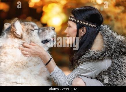 Porträt einer jungen Frau mit einem Alaska Malamute Hund im Wald vor dem Hintergrund der Natur Stockfoto