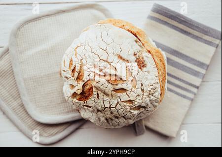 Brot mit selbstgemachtem Sauerteigbrot in der Hauptküche auf weißem Holzhintergrund. Stockfoto