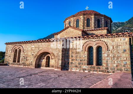Eine byzantinische Kirche in Christianoupolis, Griechenland, mit einem Kuppeldach, bogenförmigen Fenstern und komplizierten Ziegelmauern unter warmem Sonnenlicht. Stockfoto