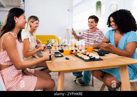 Multiethnische Gruppe junger Freunde, die sich zu Hause treffen und Sushi essen - multiethnische Happy People, die sich beim Mittagessen verbinden Stockfoto