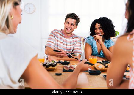 Multiethnische Gruppe junger Freunde, die sich zu Hause treffen und Sushi essen - multiethnische Happy People, die sich beim Mittagessen verbinden Stockfoto