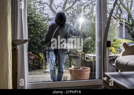 Symbolisches Bild von Einbruch, Täter spioniert auf einer Wohnung von der Gartenseite, tagsüber Stockfoto