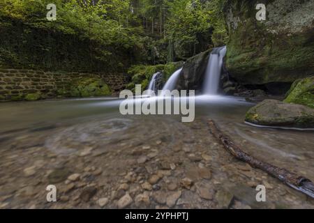 Kaskadenteich, Wasserfall unter einer kleinen Fußgängerbrücke, Müllerthal Trail, Waldbillig, Luxemburg, Europa Stockfoto