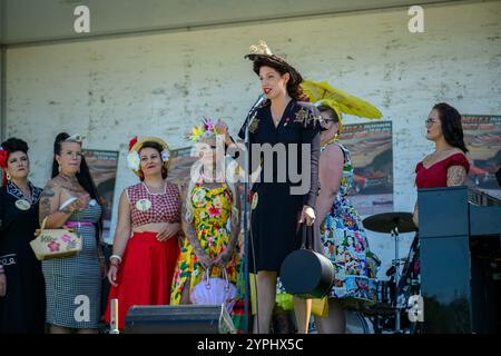 Lebendige Vintage-Mode wird lebendig, wenn eine Gruppe von Frauen ihre einzigartigen Stile auf der Bühne auf einem lebhaften lokalen Festival präsentiert und die aud anspricht Stockfoto