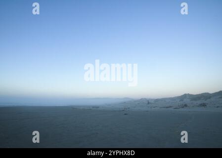 Blick über den Strand in der Abenddämmerung mit blauem Licht am Horizont über das Meer. Stockfoto
