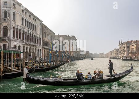 Venedig, Italien - 8. Februar 2024: Architektur von Venedig, Paläste und schöne Häuser entlang des Canal Grande mit einem Gondoliere im Vordergrund, Italien Stockfoto