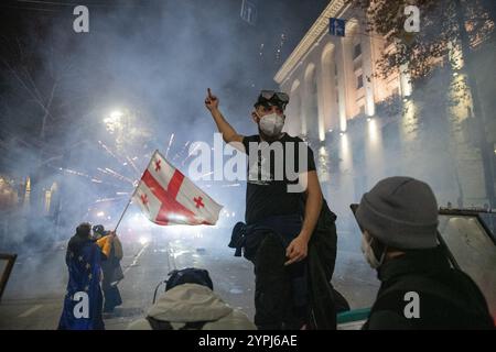 1. Dezember 2024, Tiflis, Georgien. Ein pro-europäischer Demonstrant gibt den Mittelfinger auf einer Barrikade, während ein Feuerwerk auf die Polizei geschossen wird. Quelle: Jay Kogler/Alamy Live News Stockfoto