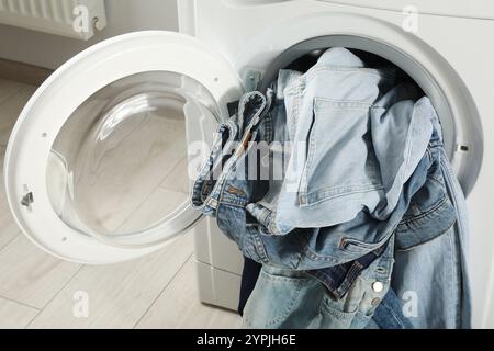 Waschmaschine mit schmutzigen Jeans und anderen Denim-Kleidern drinnen, Nahaufnahme Stockfoto