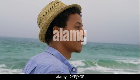 Seitenansicht eines afroamerikanischen Mannes mit Hut, der am Strand steht Stockfoto
