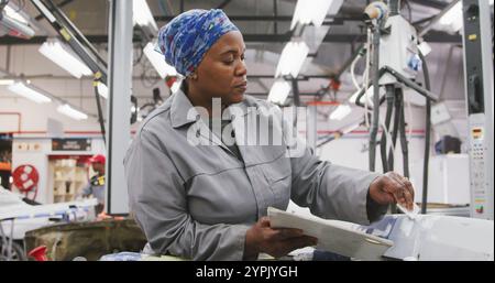 Afroamerikanerin, die in einer Werkstatt in der Stadt arbeitet, malt in Slo eine Karosserie eines Autos Stockfoto